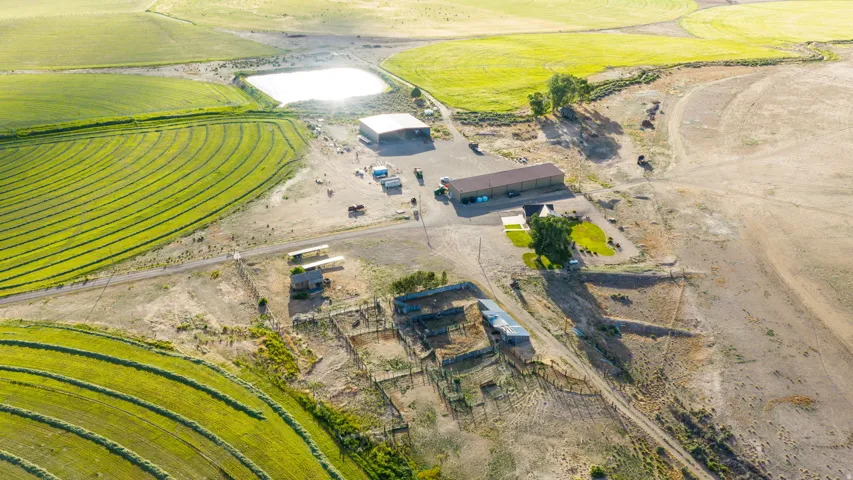 Expansive agricultural property featuring cultivated fields, a substantial barn structure, and multiple outbuildings