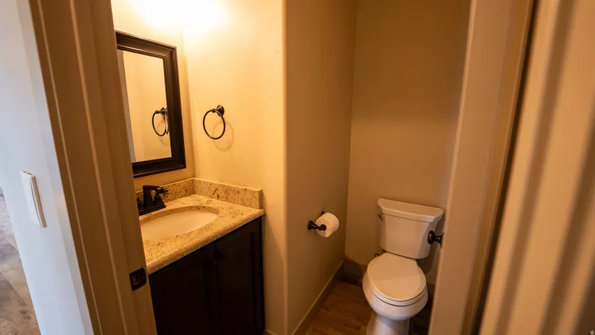 Bathroom featuring a vanity with a light-colored countertop, dark wood-finish cabinetry, an oval undermount sink, and a framed mirror