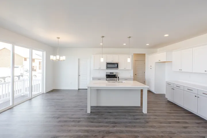 Kitchen with white cabinetry, dark wood-style flooring, stainless steel appliances, an island with sink, and a chandelier