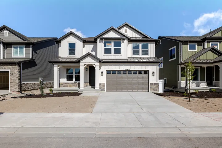 View of front of home with an attached garage, concrete driveway, a standing seam roof, board and batten siding, and covered porch