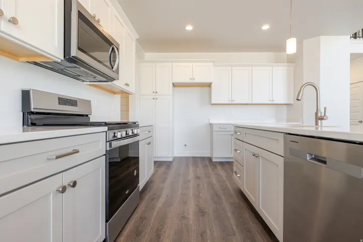 Kitchen with stainless steel appliances, white cabinetry, dark wood-type flooring, and pendant lighting