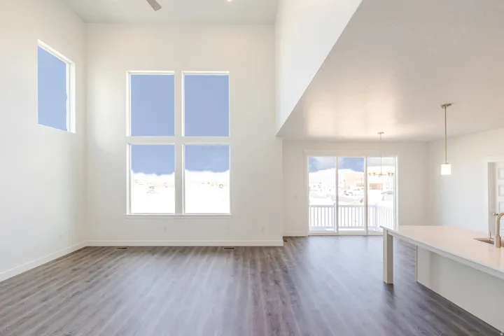 Unfurnished living room featuring dark wood-type flooring, ceiling fan, and a high ceiling