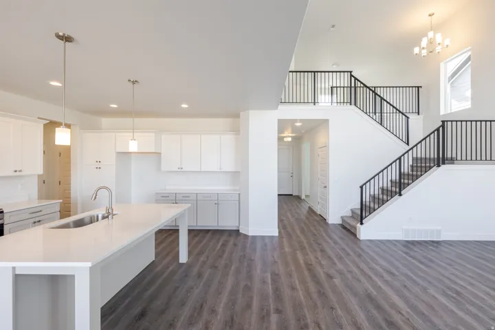 Kitchen with white cabinets, a center island with sink, dark wood finished floors, a kitchen bar, and light stone counters