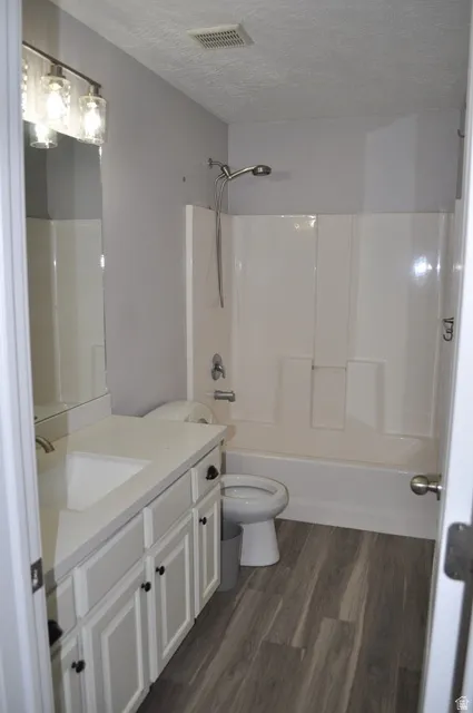 Bathroom featuring vanity, dark wood finished floors, a textured ceiling, and bathtub / shower combination