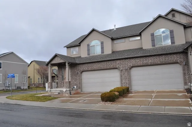 Traditional-style home featuring driveway, brick siding, and a garage