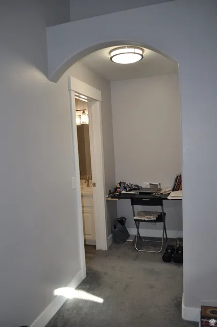 Hall featuring arched walkways and dark colored carpet