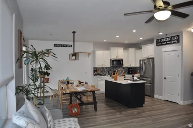 Kitchen featuring white cabinetry, stainless steel appliances, light countertops, a kitchen island with sink, and tasteful backsplash