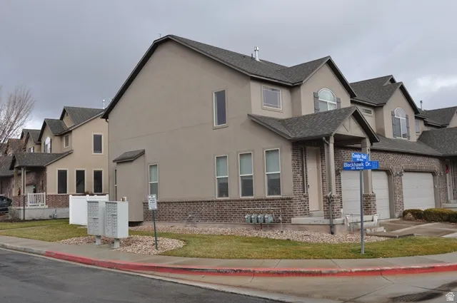 View of front of home with stucco siding, a garage, and brick siding