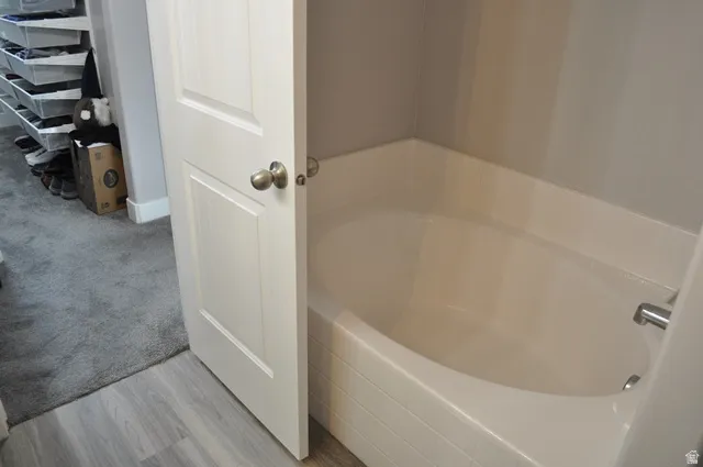Full bath with a garden tub, light carpet, and light wood-style flooring