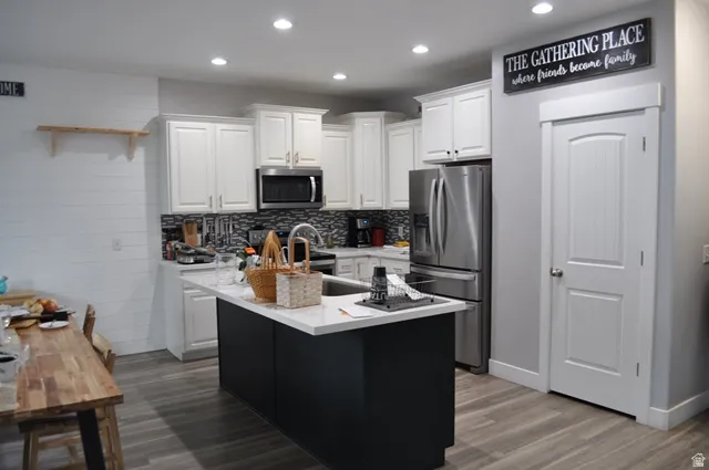 Kitchen featuring white cabinetry, a center island with sink, stainless steel appliances, recessed lighting, and tasteful backsplash