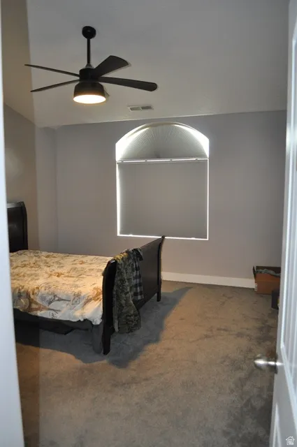 Bedroom with dark carpet and ceiling fan