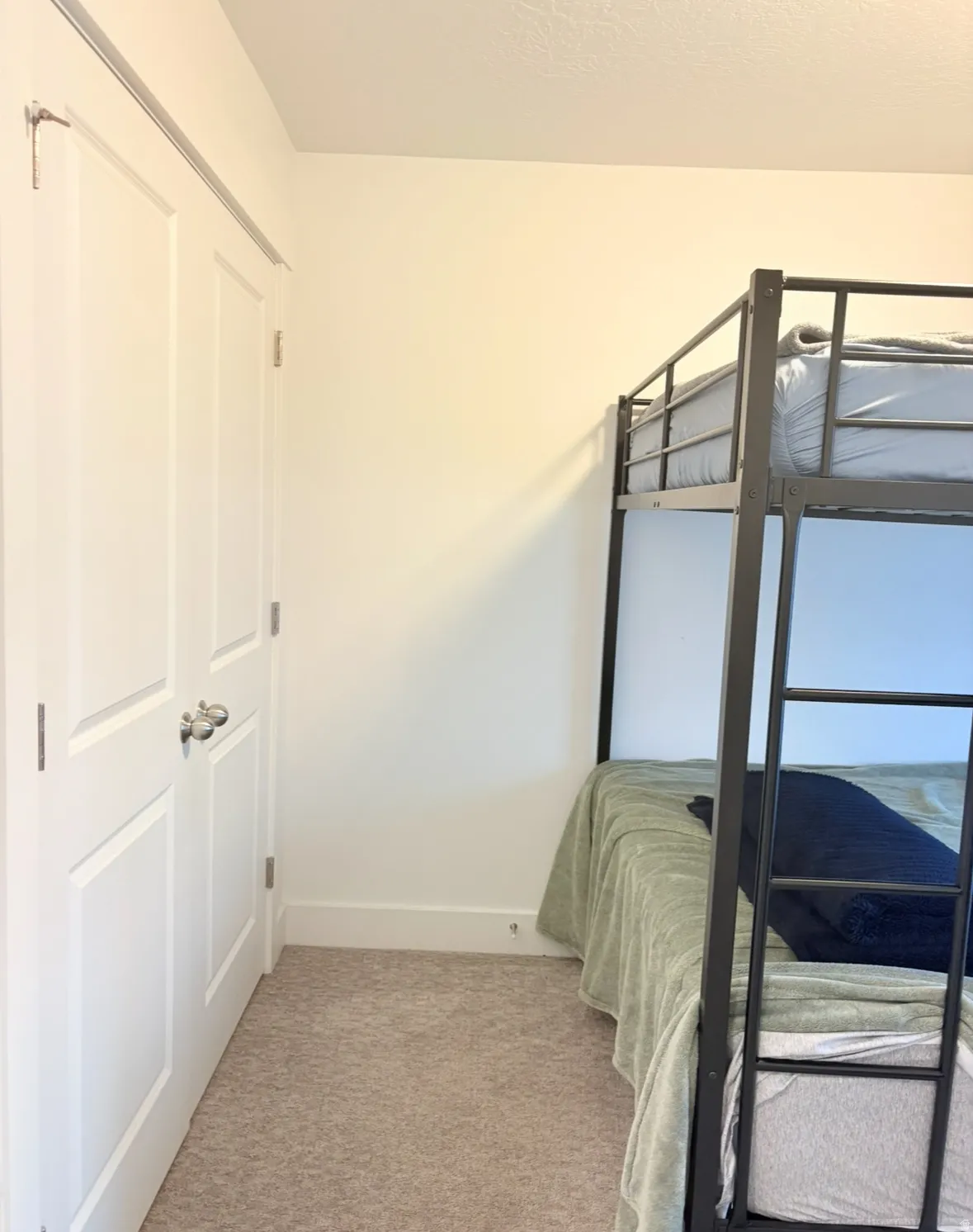 Bedroom with light colored carpet and baseboards
