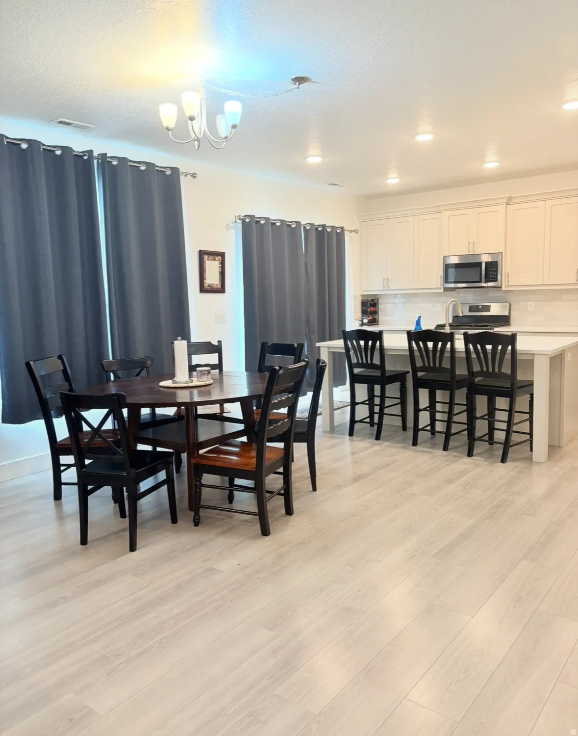 Dining room with light wood finished floors, a chandelier, and a textured ceiling
