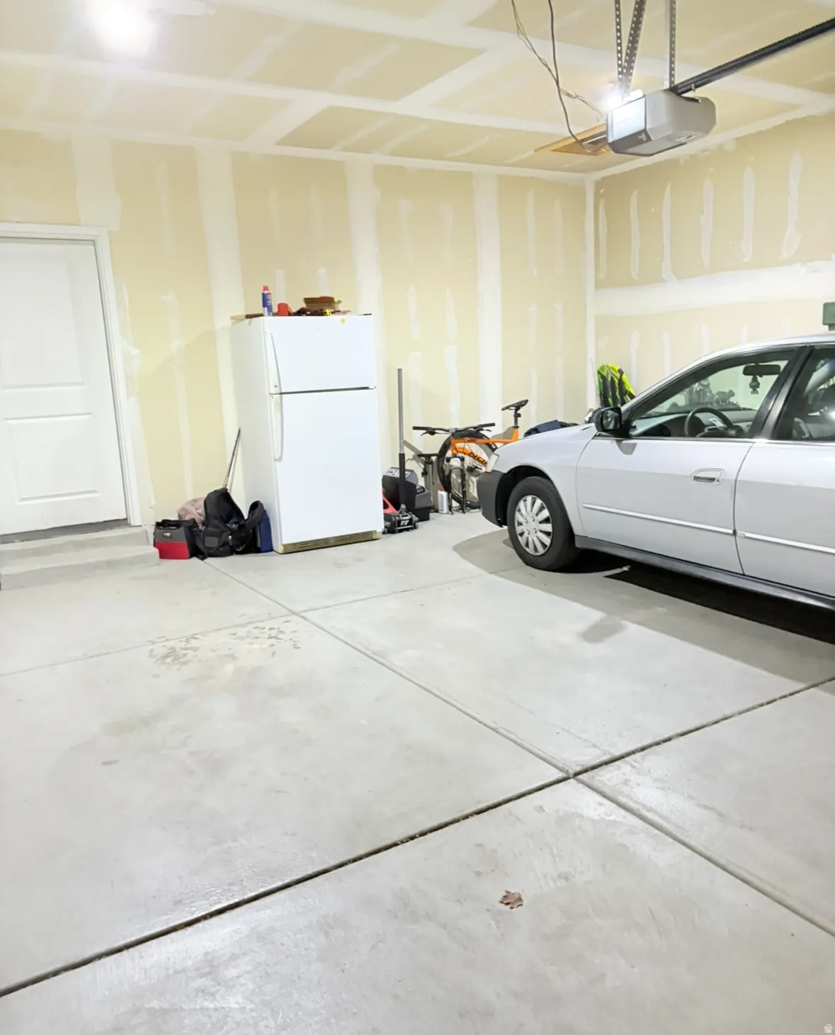 Garage with freestanding refrigerator and a garage door opener