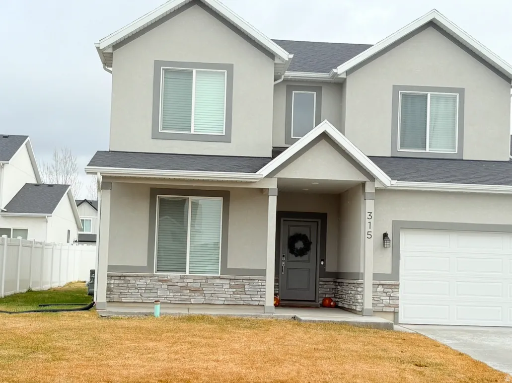 Traditional-style home with stone siding, a shingled roof, stucco siding, and a garage