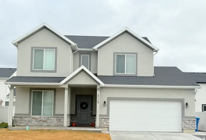 View of front of property with stone siding, concrete driveway, and a shingled roof