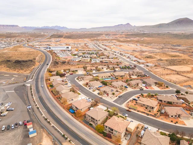Aerial view of property and surrounding area featuring mountains and nearby suburban area