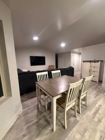 Dining space featuring light wood finished floors, a barn door, and lofted ceiling