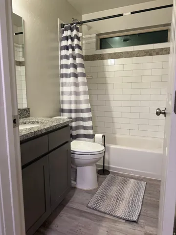 Full bathroom featuring vanity, dark wood-style flooring, and shower / bathtub combination with curtain