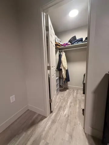 Walk in closet with light wood finished floors