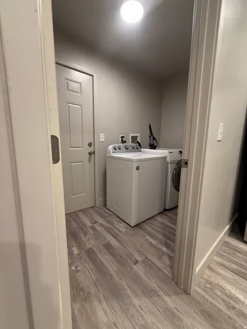 Laundry room with light wood-style flooring and washing machine and dryer