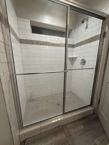 Bathroom with a shower stall and wood finished floors