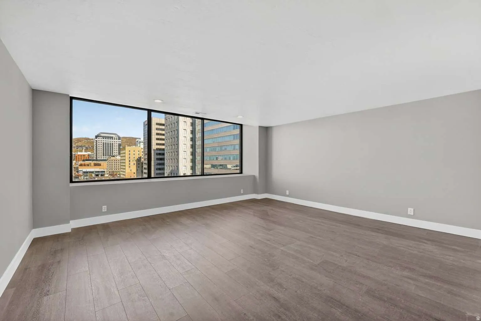 Empty room with dark wood-style floors and a city view