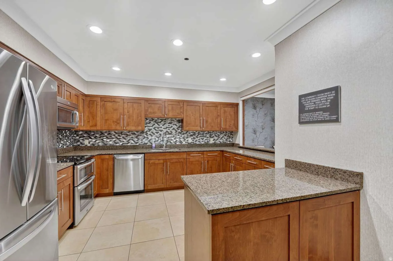 Kitchen with wood finish cabinetry, stainless steel appliances, light stone counters, a peninsula, and recessed lighting