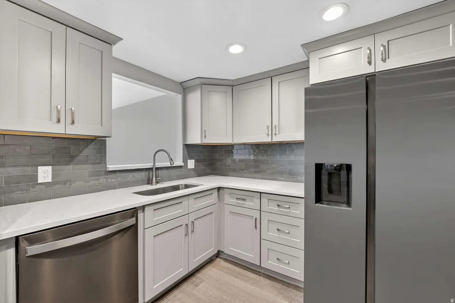 Kitchen featuring stainless steel appliances, light stone counters, light wood-style flooring, recessed lighting, and tasteful backsplash