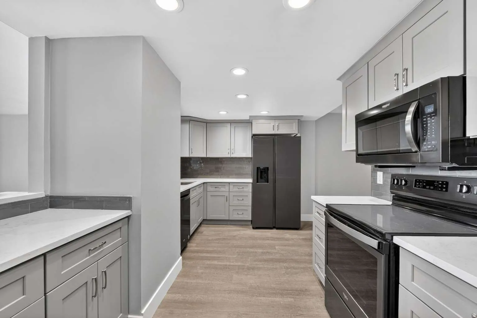 Kitchen featuring black appliances, gray cabinetry, decorative backsplash, light stone counters, and recessed lighting