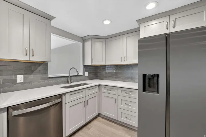 Kitchen featuring stainless steel appliances, light stone counters, light wood-style flooring, recessed lighting, and tasteful backsplash