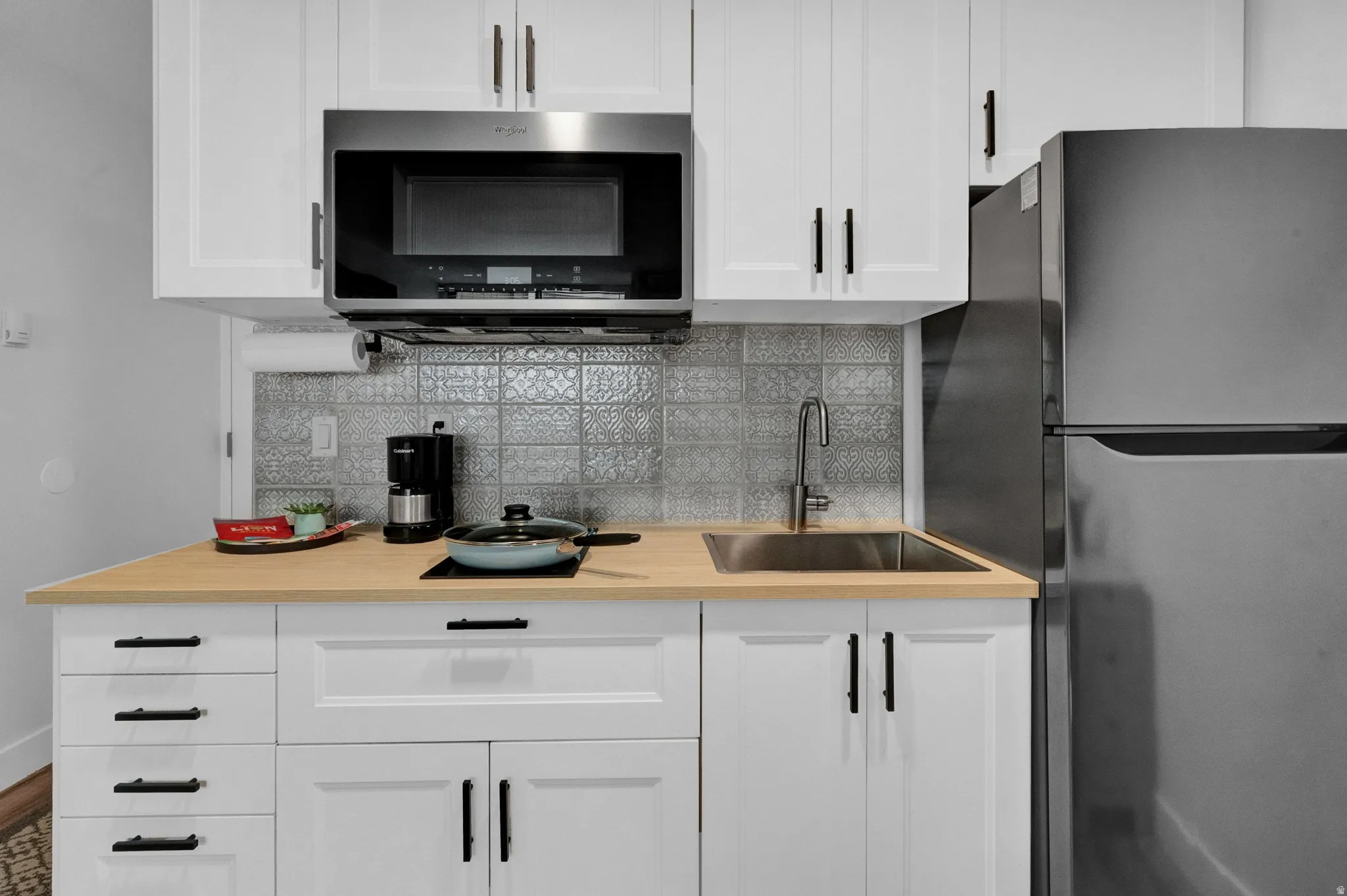 Kitchen with light countertops, appliances with stainless steel finishes, backsplash, and white cabinets