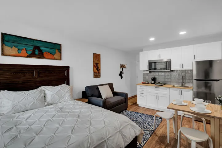 Bedroom with freestanding refrigerator, wood finished floors, and recessed lighting