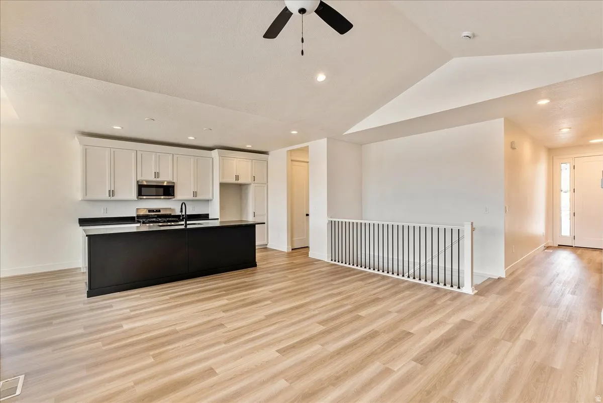 Kitchen featuring open floor plan, light wood-style floors, recessed lighting, stainless steel appliances, and a center island with sink