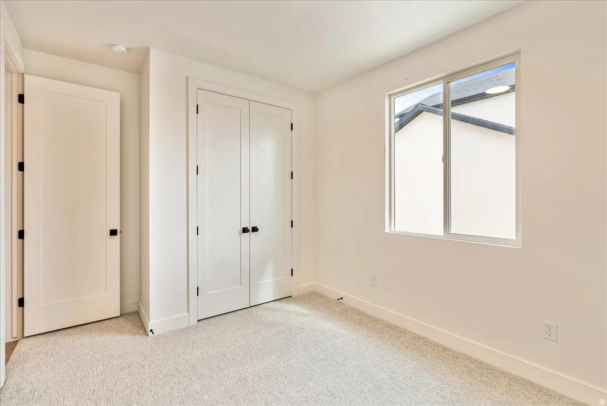 Unfurnished bedroom featuring light carpet and a closet