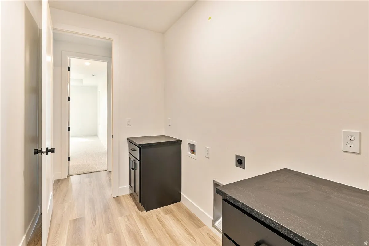 Laundry room with hookup for an electric dryer, hookup for a washing machine, cabinet space, and light wood-style flooring