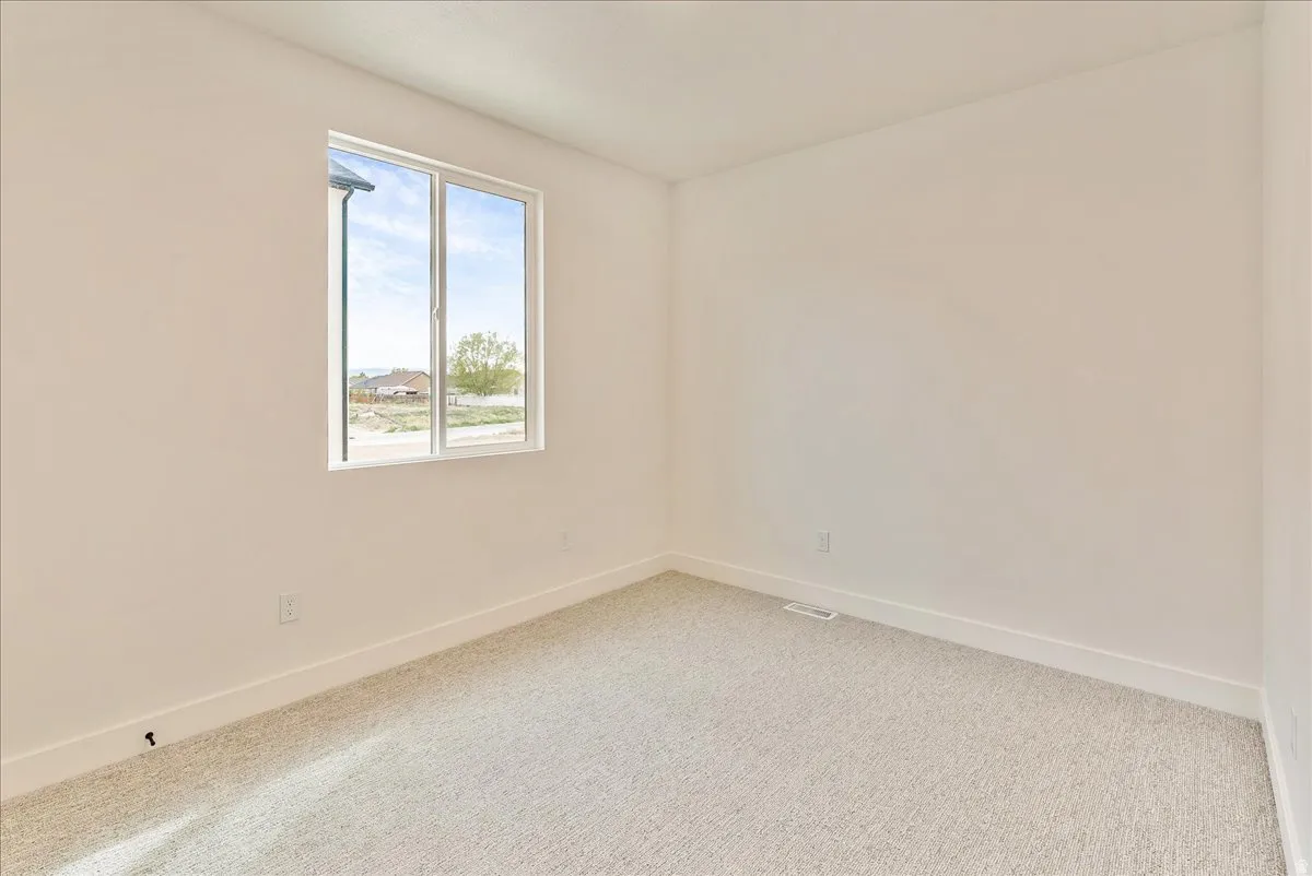 Empty room featuring baseboards and light carpet
