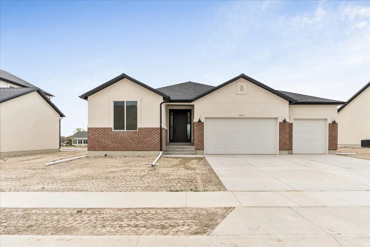 View of front facade with a garage, stucco siding, driveway, and brick siding