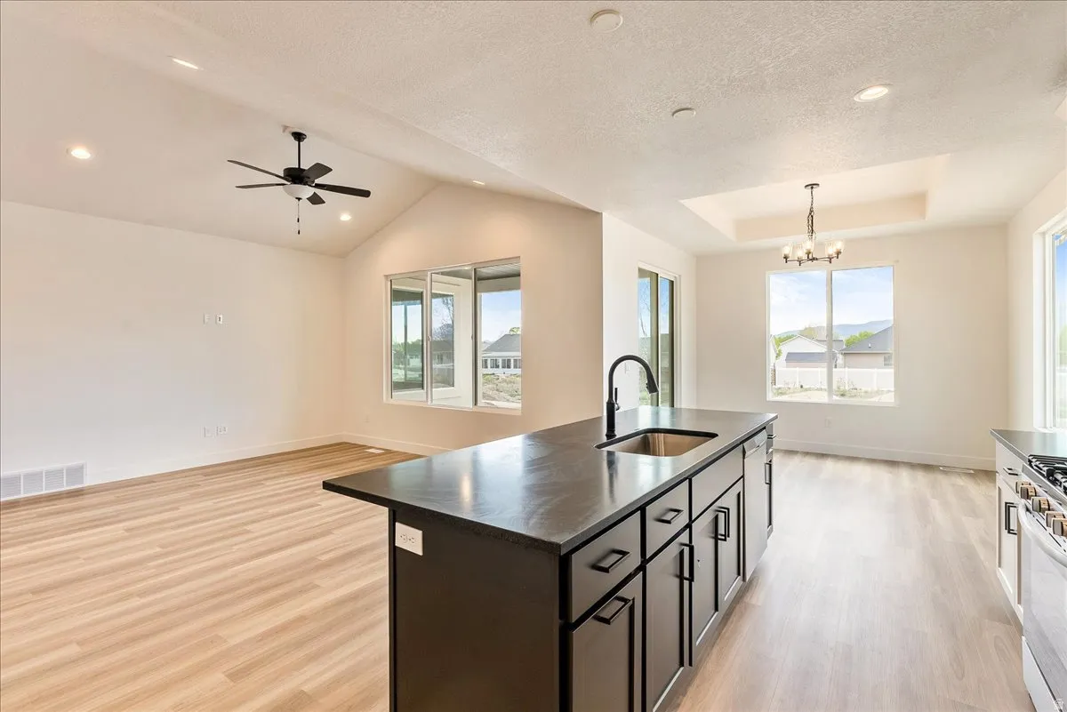 Kitchen featuring an island with sink, light wood finished floors, open floor plan, a chandelier, and stainless steel appliances