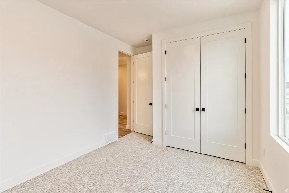 Unfurnished bedroom featuring light carpet and a closet