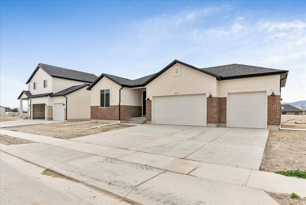 View of front facade with an attached garage, concrete driveway, and brick siding