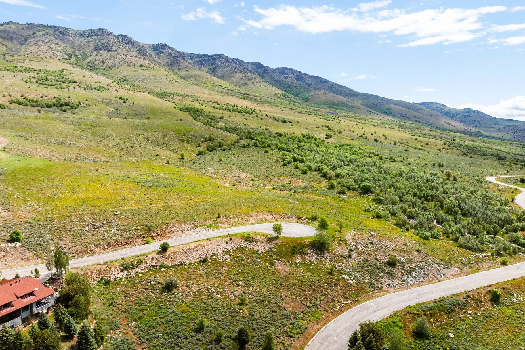 Expansive mountain landscape featuring varied terrain and a paved winding road