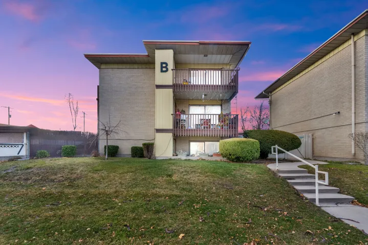 Rear view of property featuring a balcony, brick siding, and stairs