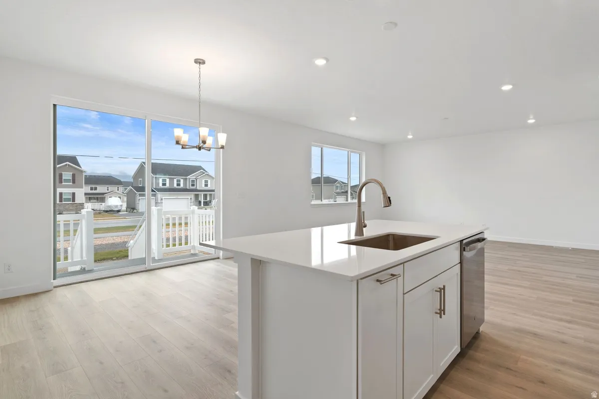 Kitchen featuring white cabinets, light wood finished floors, decorative light fixtures, light stone counters, and recessed lighting