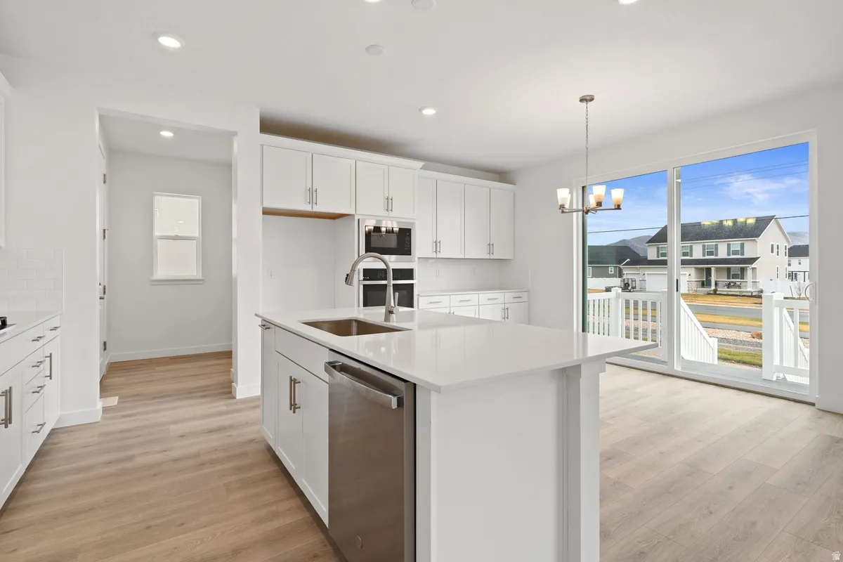 Kitchen with white cabinetry, appliances with stainless steel finishes, pendant lighting, a kitchen island with sink, and recessed lighting