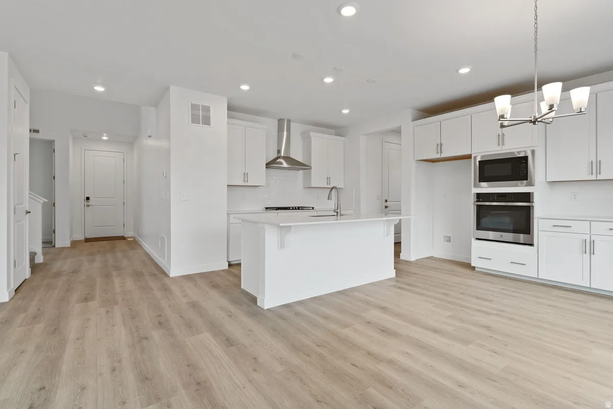 Kitchen featuring stainless steel appliances, white cabinets, tasteful backsplash, light wood-style flooring, and recessed lighting