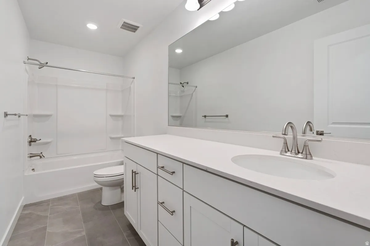 Full bath featuring vanity, bathing tub / shower combination, dark tile patterned flooring, and recessed lighting