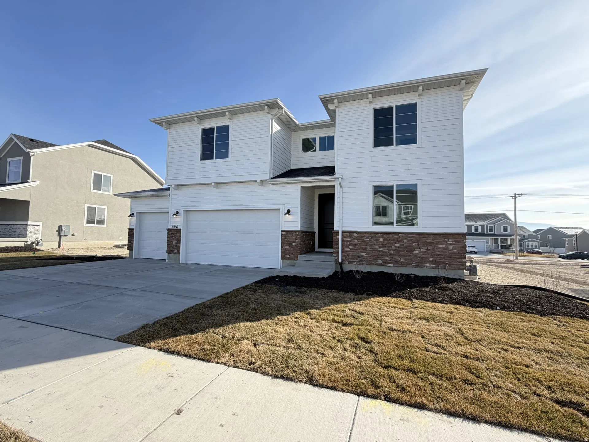 View of front of home with brick siding, driveway, an attached garage, and a front lawn