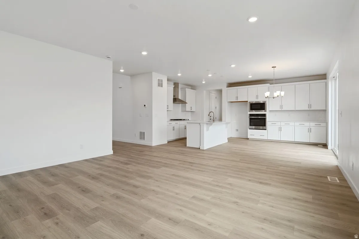 Unfurnished living room featuring a chandelier, recessed lighting, and light wood-type flooring