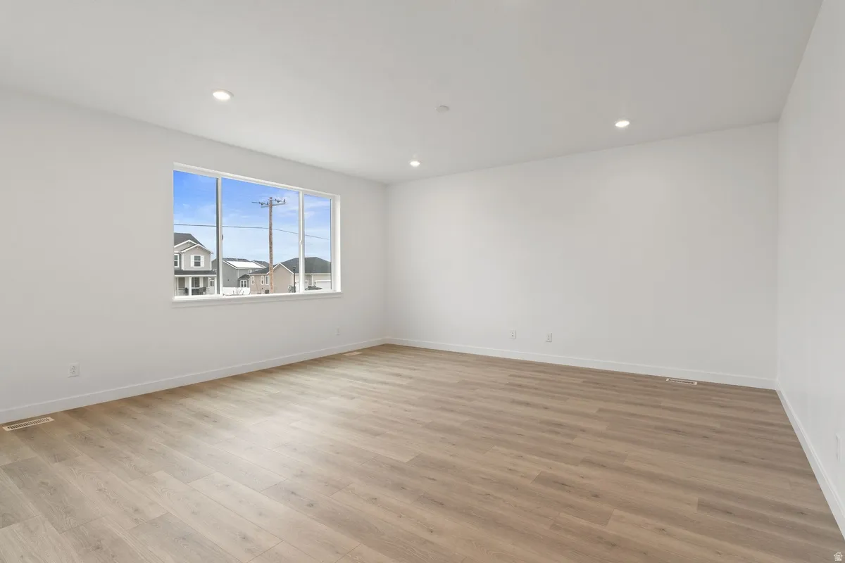 Empty room featuring light wood-type flooring and recessed lighting
